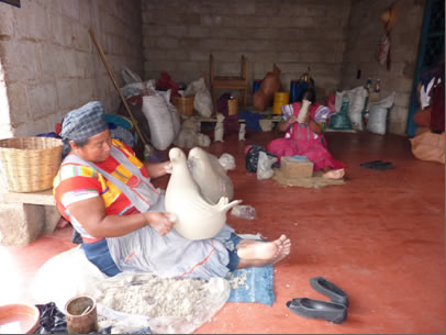 seated woman artisan holding fired clay shape of a dove